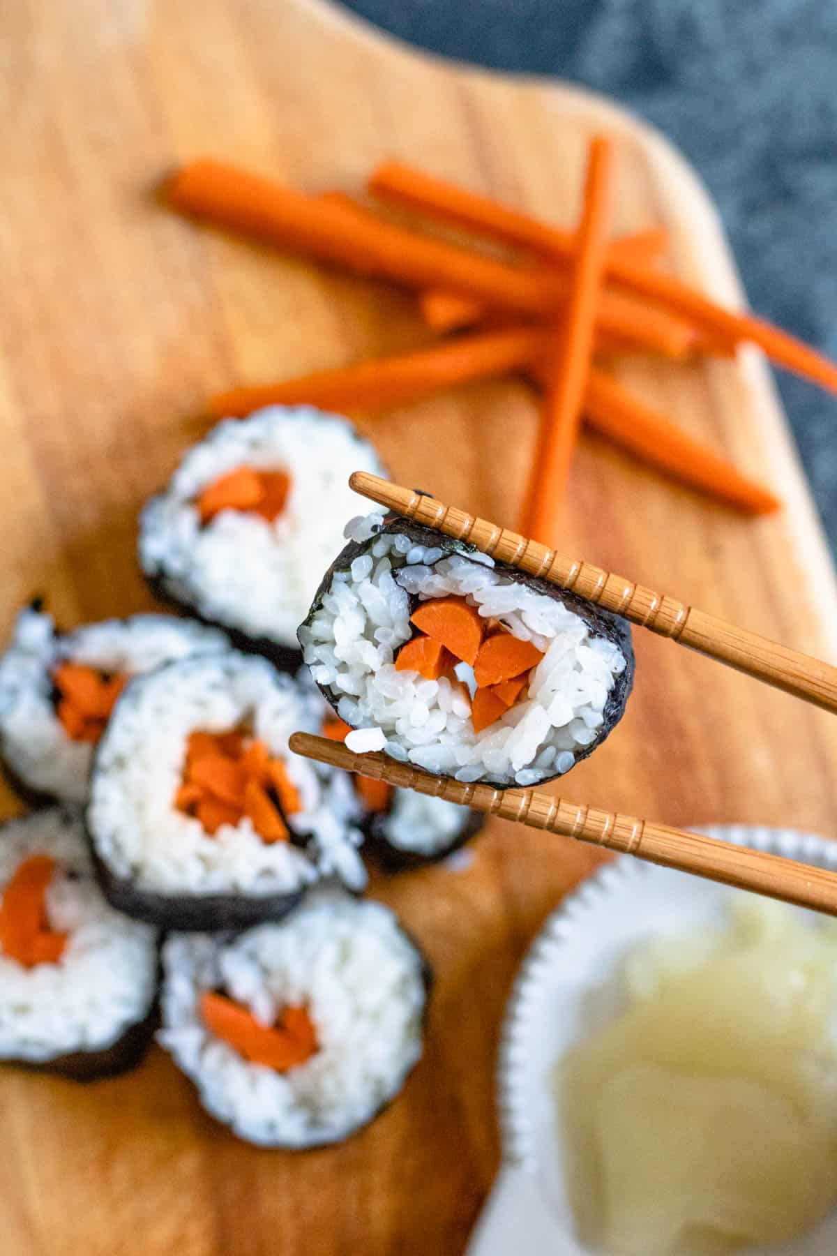 Chopsticks holding up a slice of gobo sushi. 
