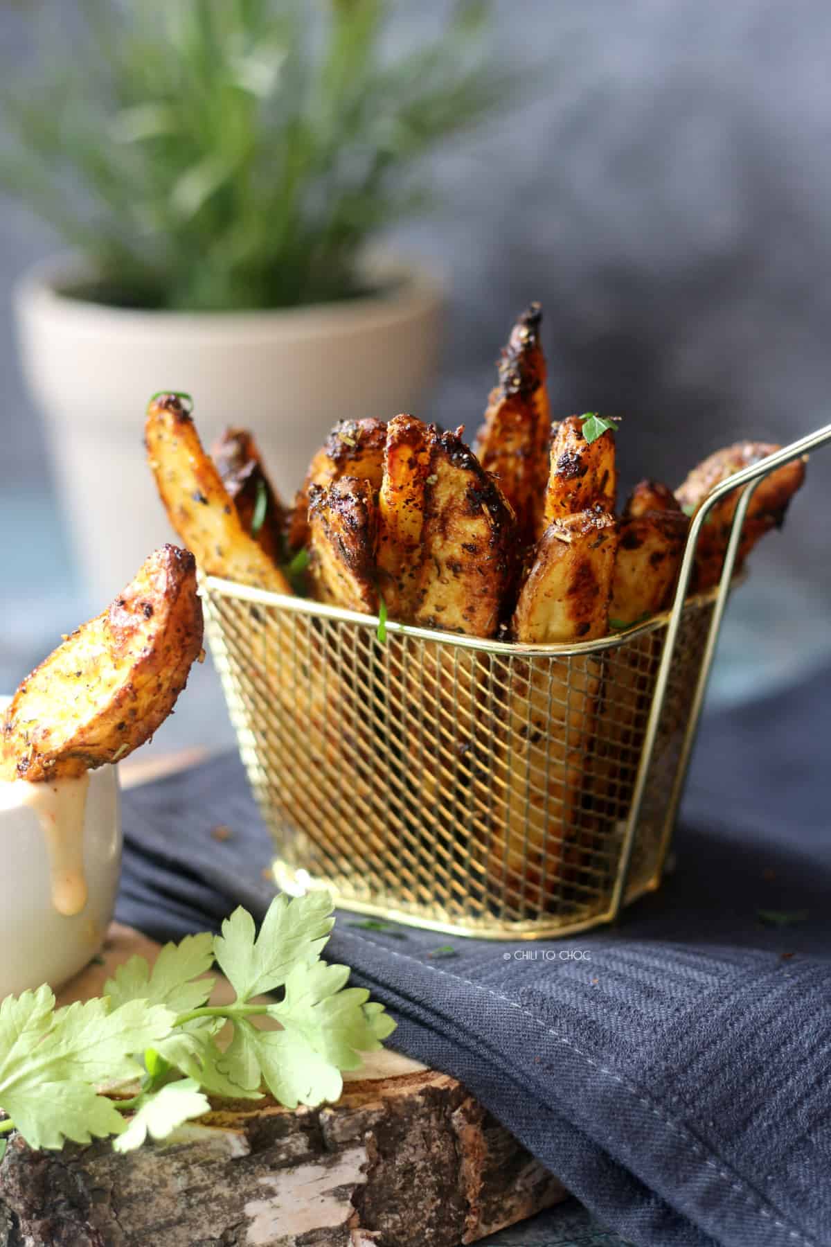 Greek style potato wedges in a small metal basket. 