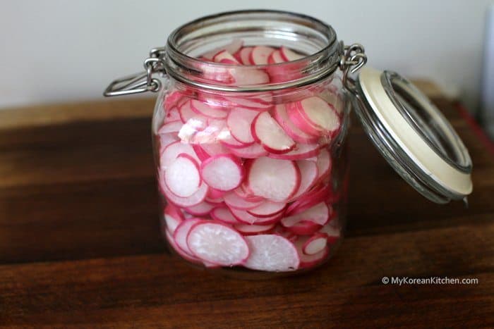 Pickled radishes sliced in a glass jar. 
