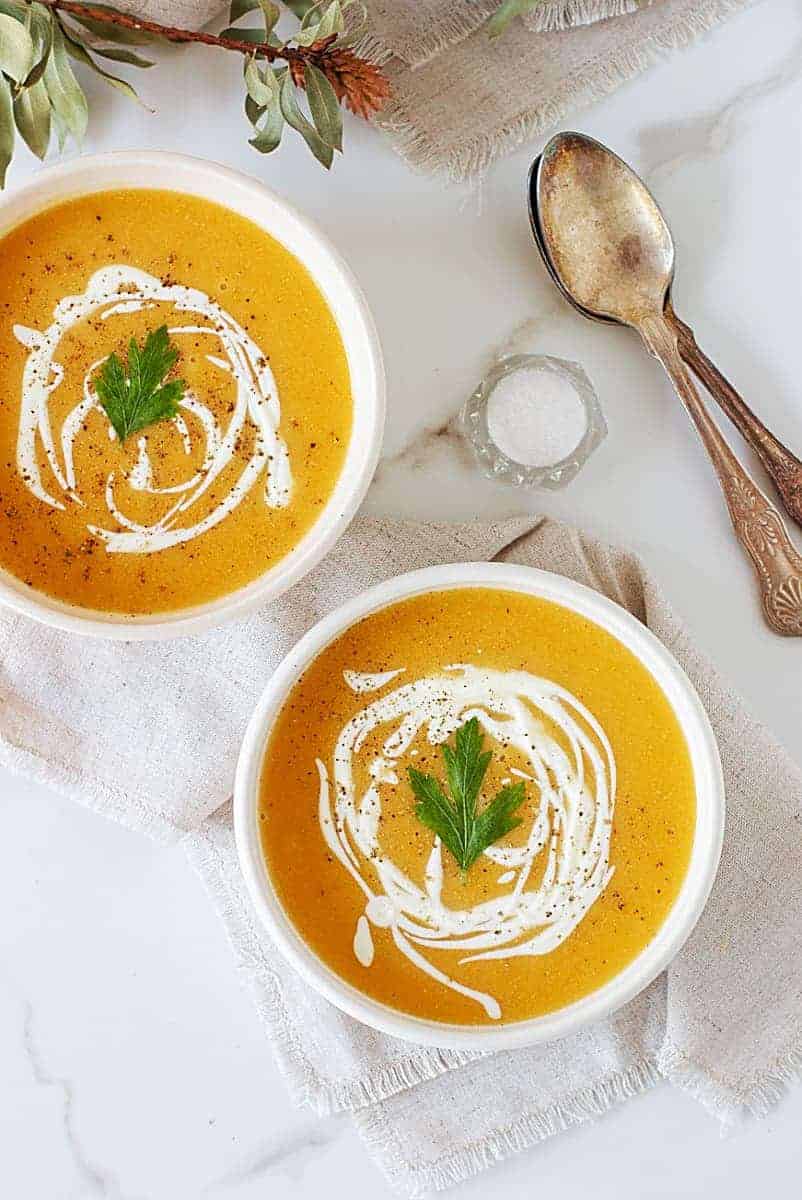Two bowls of butternut squash and lentil soup with a creamy drizzle over the top. 