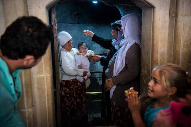 A Yazidi family baptizes an infant in the holy village of Lalish, Iraq.