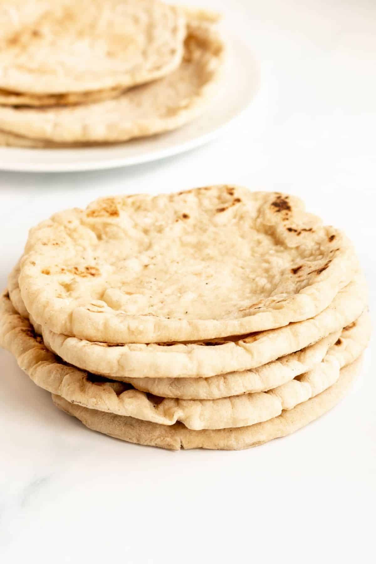 Greek pita bread stacked up on top of one another. 