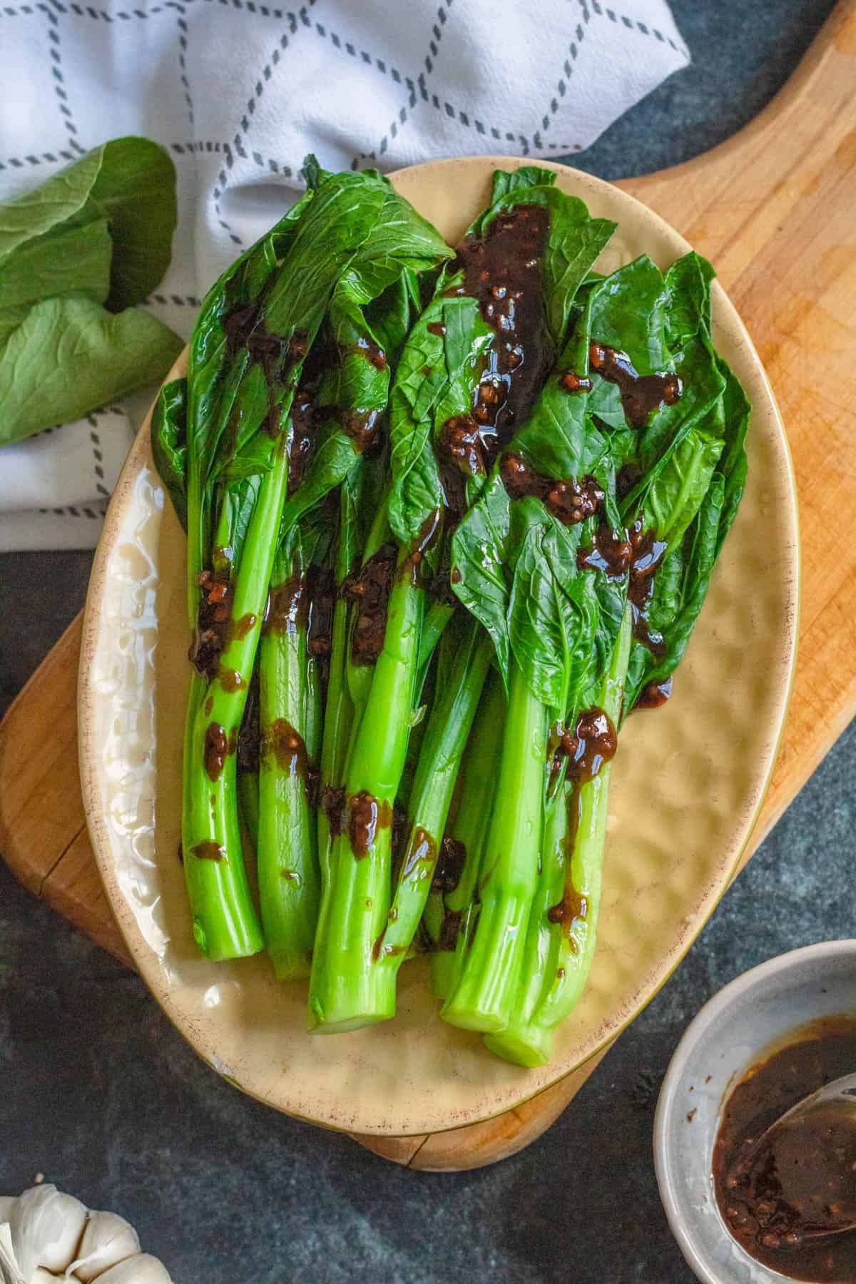 Plate of yu choy with the sauce drizzled over it on a serving plate.