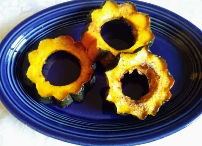 Orange cinnamon acorn squash rings sitting on a blue plate. 