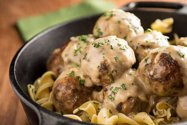 Bowl of egg noodles covered in swedish meatballs. 