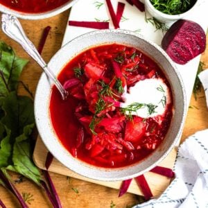 Bowl of vegetarian Borscht with a dollop of cream and fresh dill served on top.