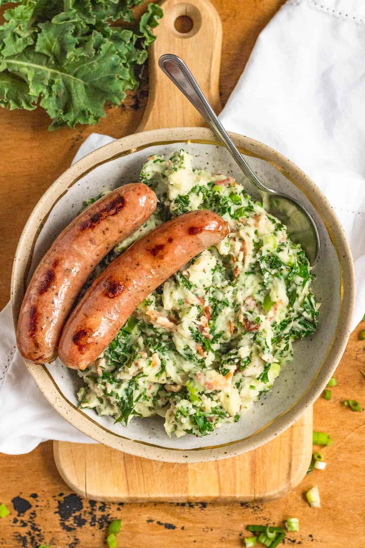 Two sausages on a plate with colcannon. 