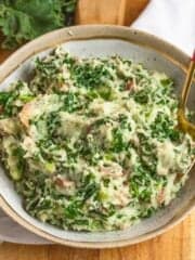 Colcannon in a large bowl with a spoon sticking out of it.