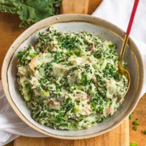 Colcannon in a large bowl with a spoon sticking out of it.