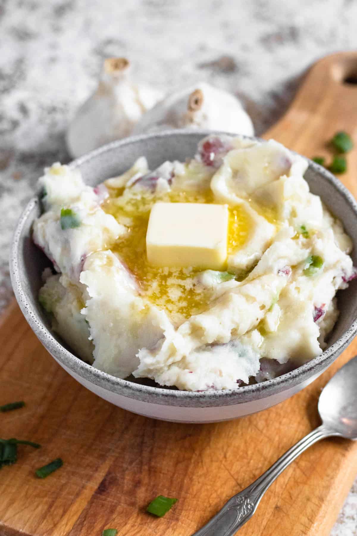 Bowl of garlic redskin mashed potatoes with a pat of butter melting on top. 