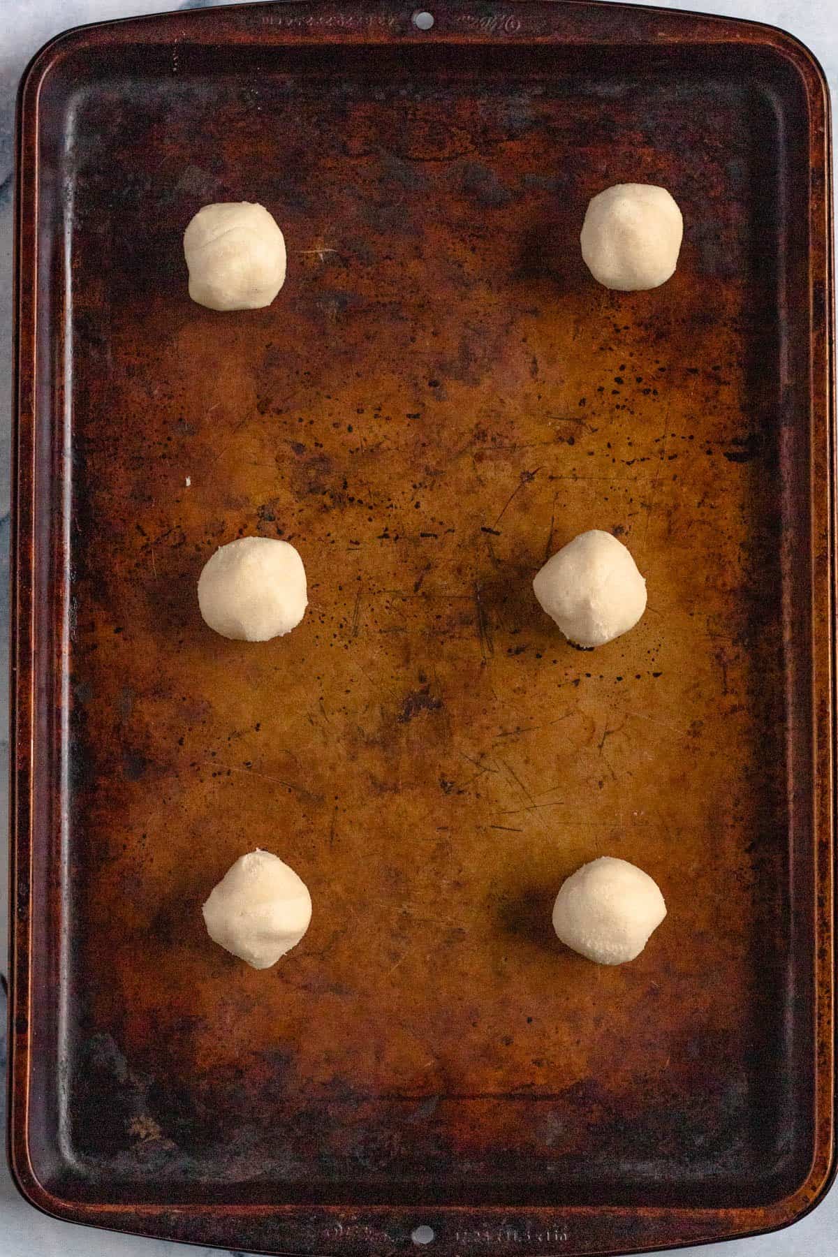 Sugar cookie dough rolled into balls and placed on a baking tray. 
