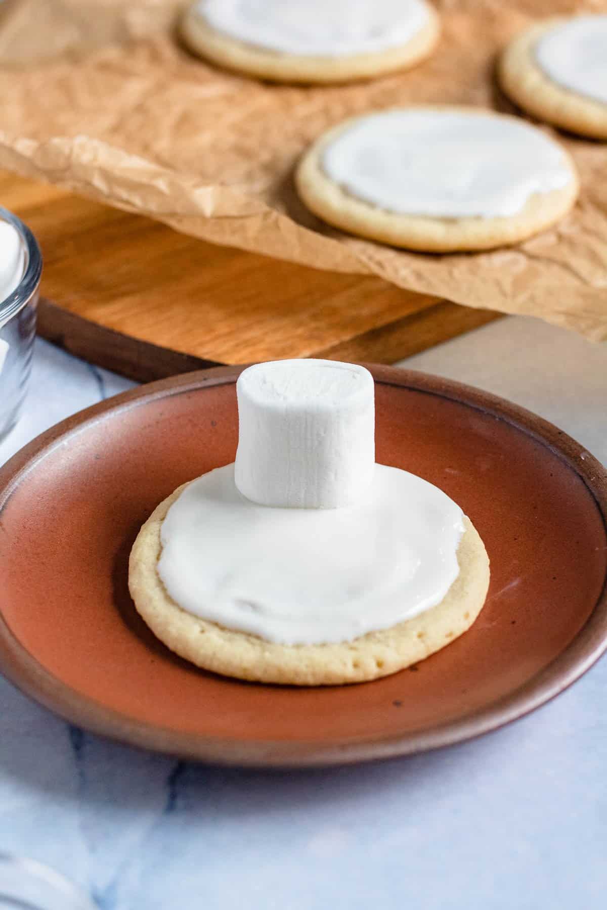 Large marshmallow added to the top of the frosted cookie. 