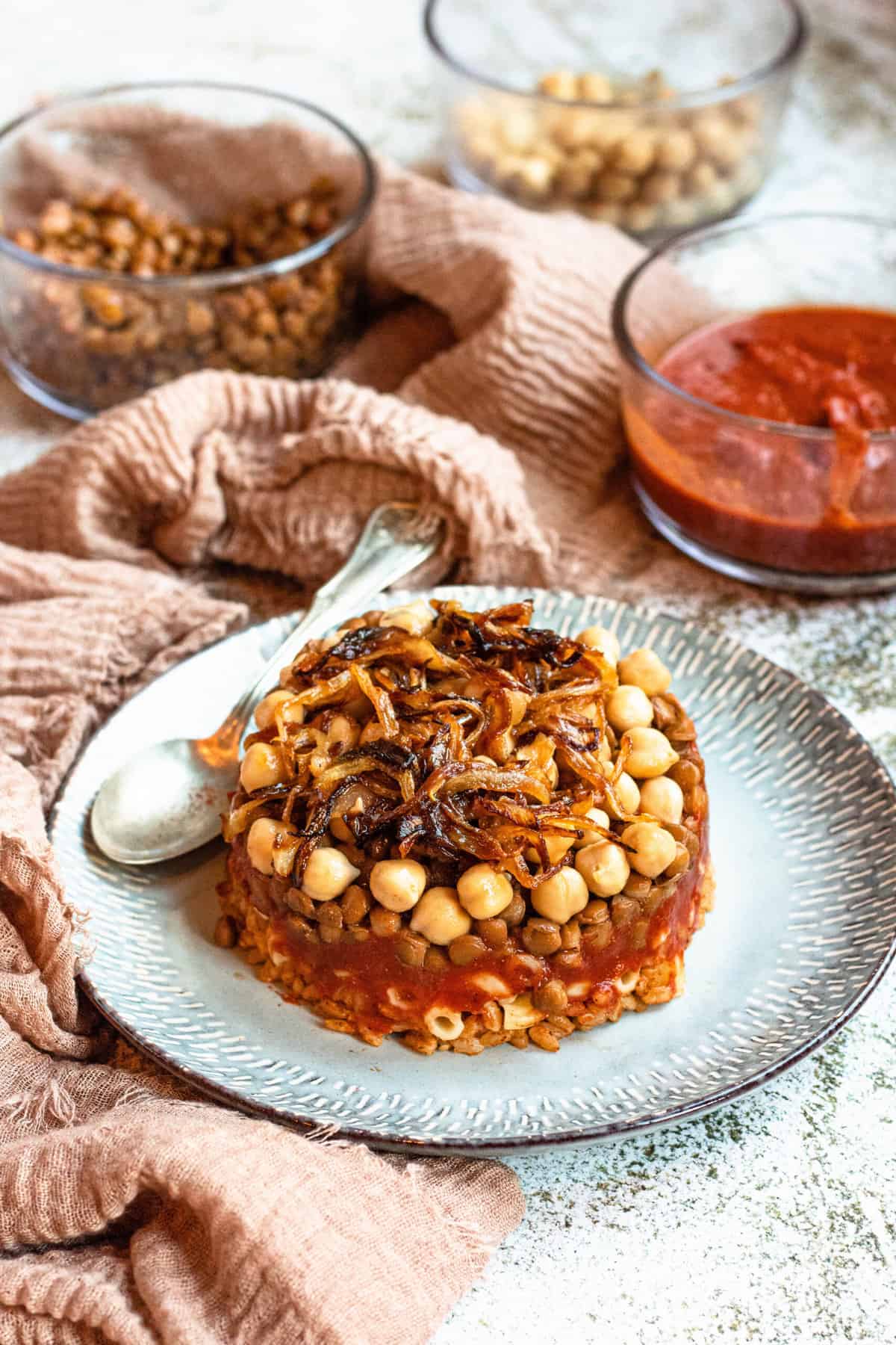 Koshari stacked and served on a plate with a spoon. 