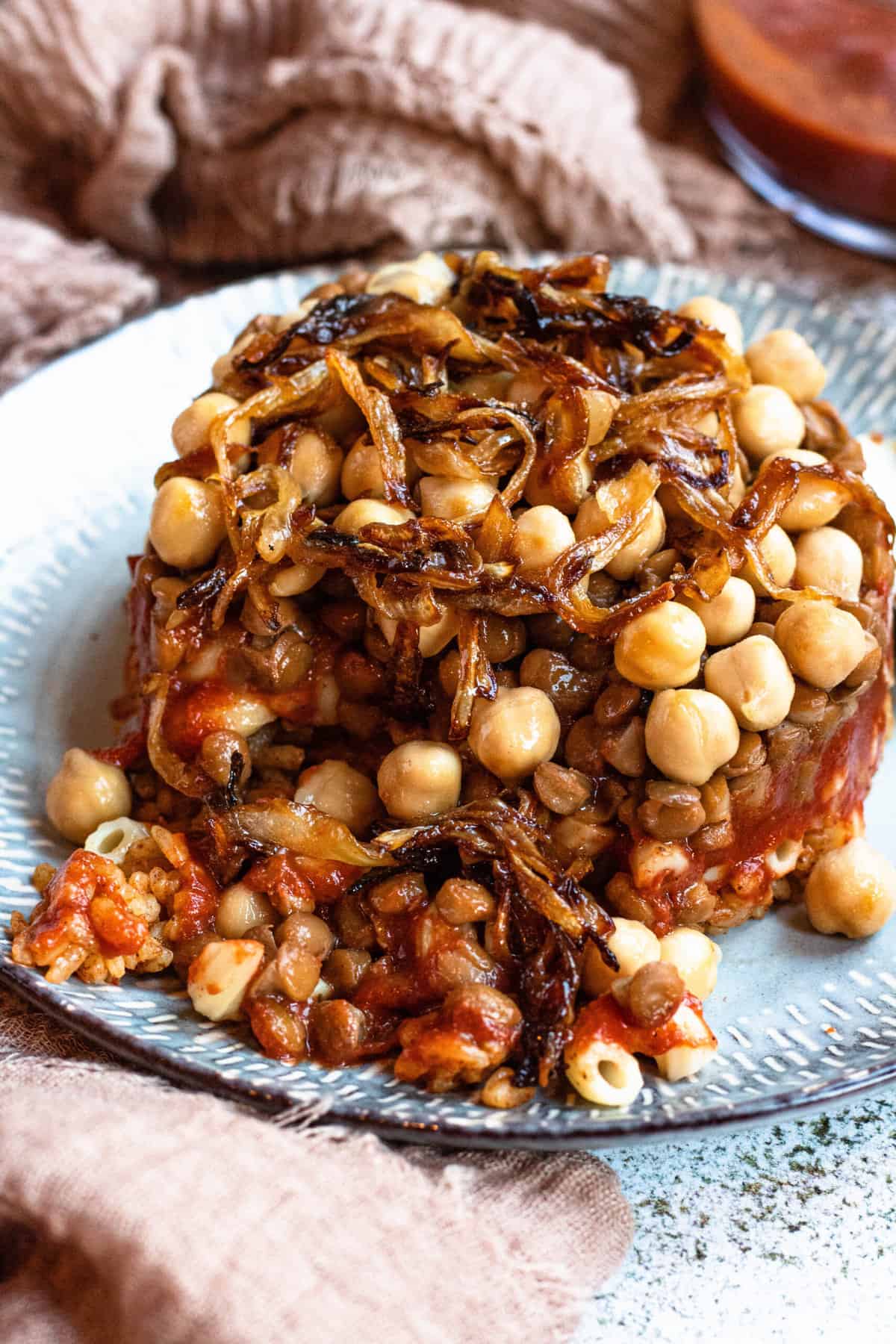 Close up of koshari served on a plate with a bit removed. 