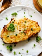 Croque Monsieur on a white plate, topped with parsley.