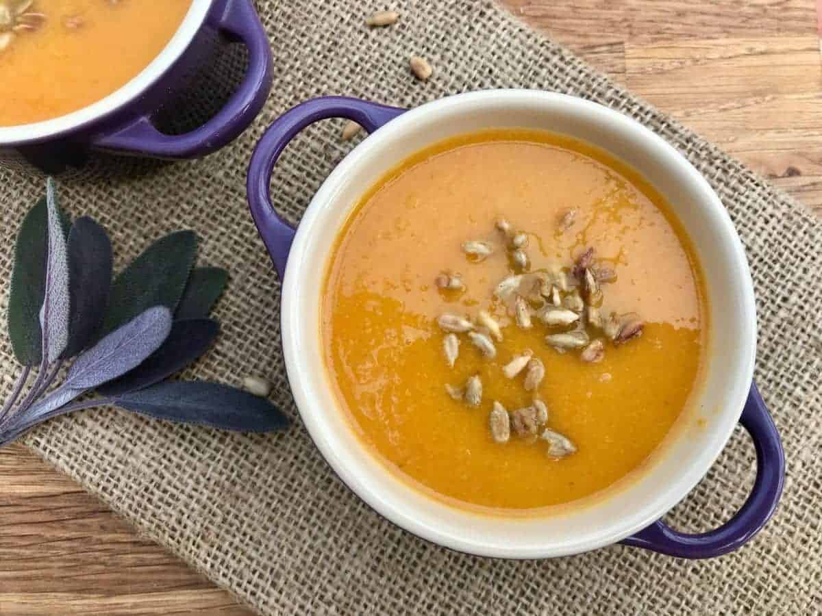 Carrot and apple soup with sunflower seeds garnished on top. 