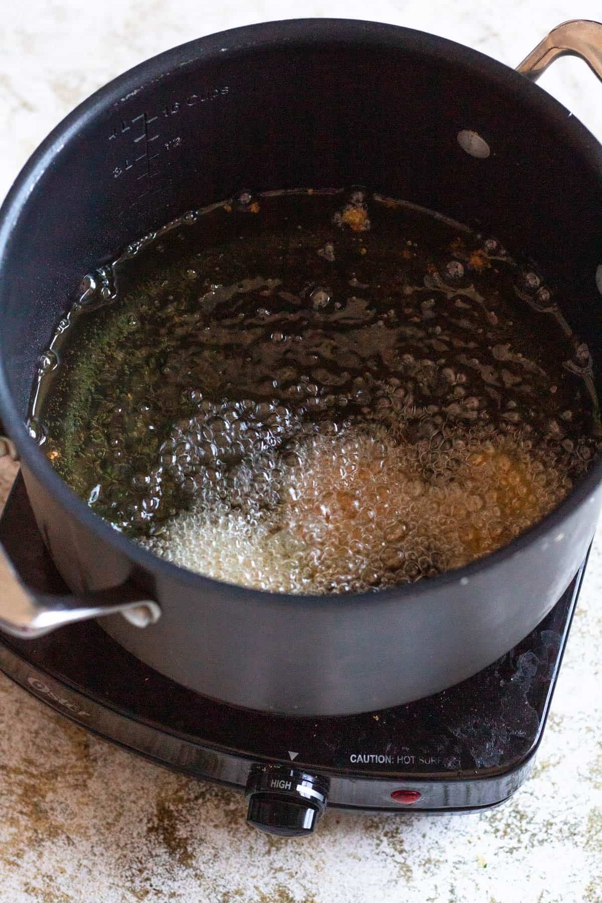 Falafel added to a pot of hot vegetable oil to fry. 