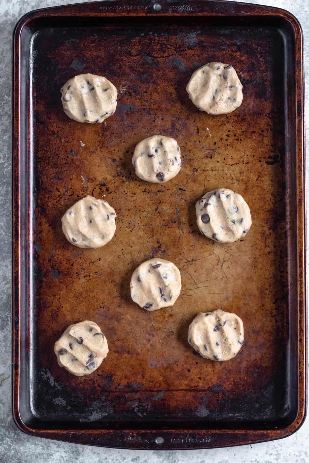 Chocolate chip cookie dough added to a baking sheet and slightly flattene after combining two pieces together. 