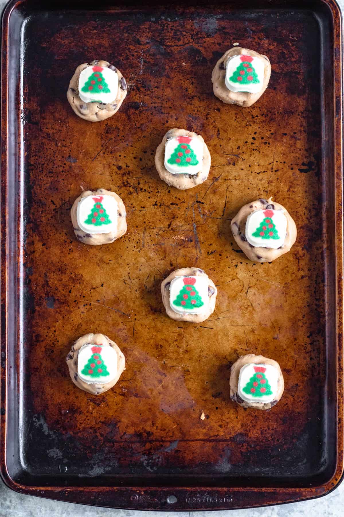 A pillsbury christmas sugar cookie placed on top of the chocolate chip cookie dough. 