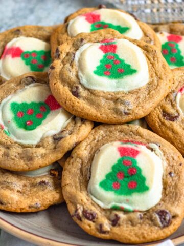 Pillsbury Christmas cookies in a pile on a plate, made by baking pillsbury christmas tree cookies on top of chocolate chip cookies.