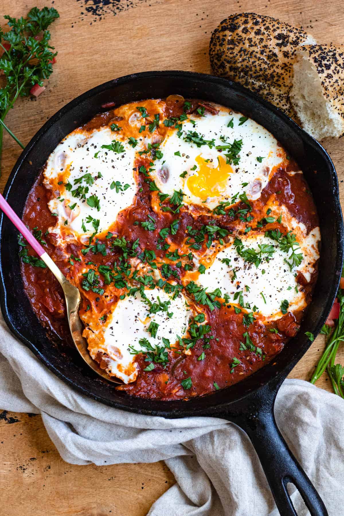 Skillet of shakshuka recipe with a serving spoon tucked into it. 