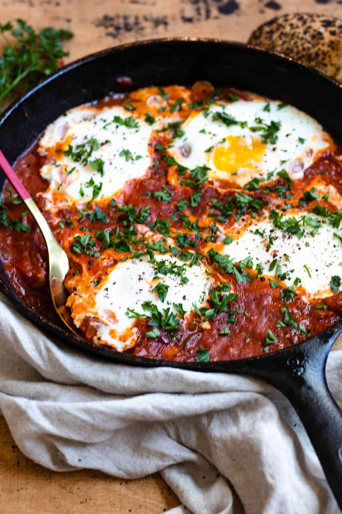 Shakshuka in a skillet and ready to serve with a spoon tucked in. 