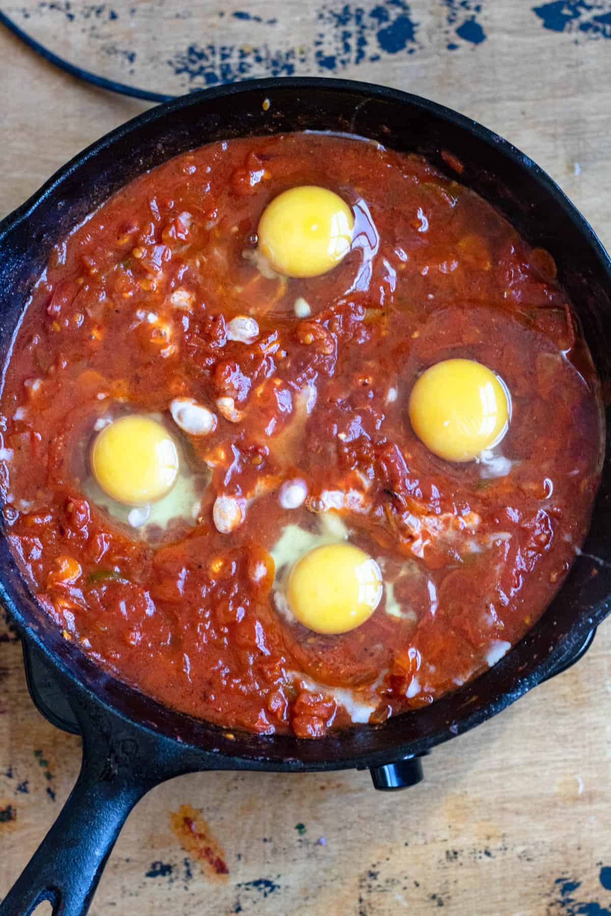 Eggs cracked and added to the tomato mixture to finish preparing Shakshuka recipe. 