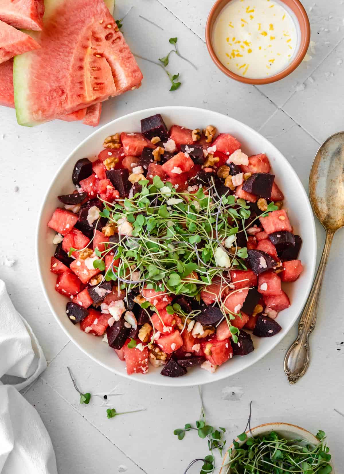 Watermelon beet salad in a bowl with a serving spoon laying next to it. 