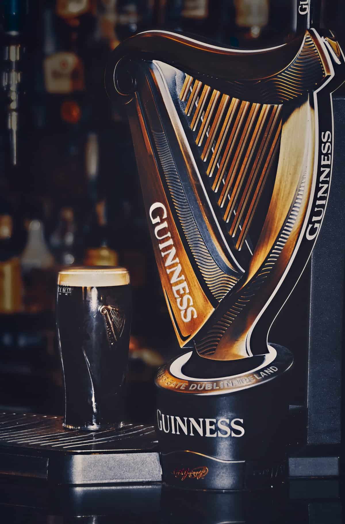 Glass of Guinness next to the famous Guinness harp 