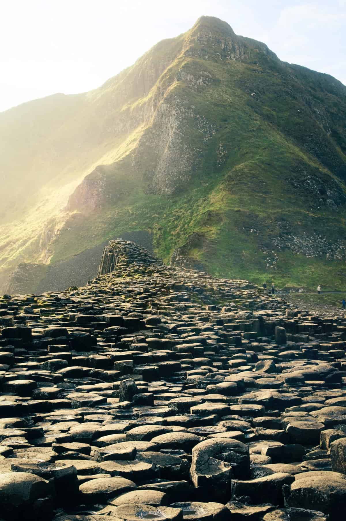 Giants Causeway stones in front of a green mountain 