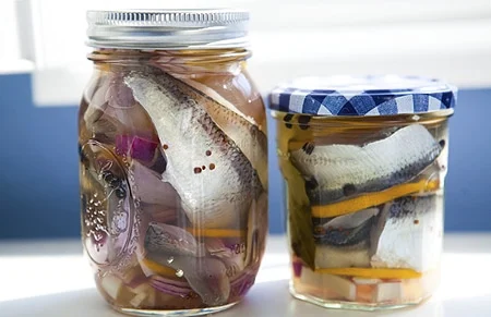 Two jars of pickled herring that are traditionally served at a Swedish christmas. 