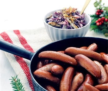 Prince sausages (prinskorv) in a pan with a side of cooked cabbage. 