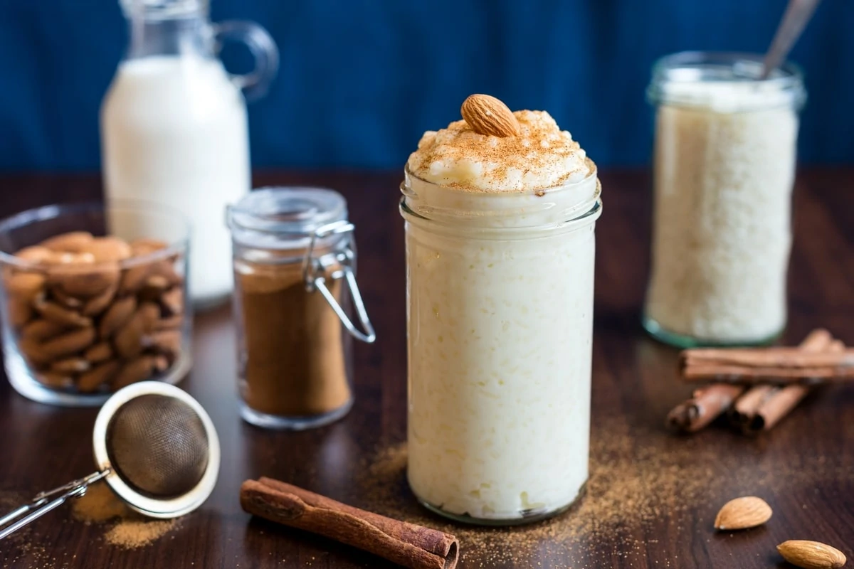 Rice Pudding (Risgrynsgröt) served in a tall mason jar with a sprinkling of cinnamon and a whole almond on top. 