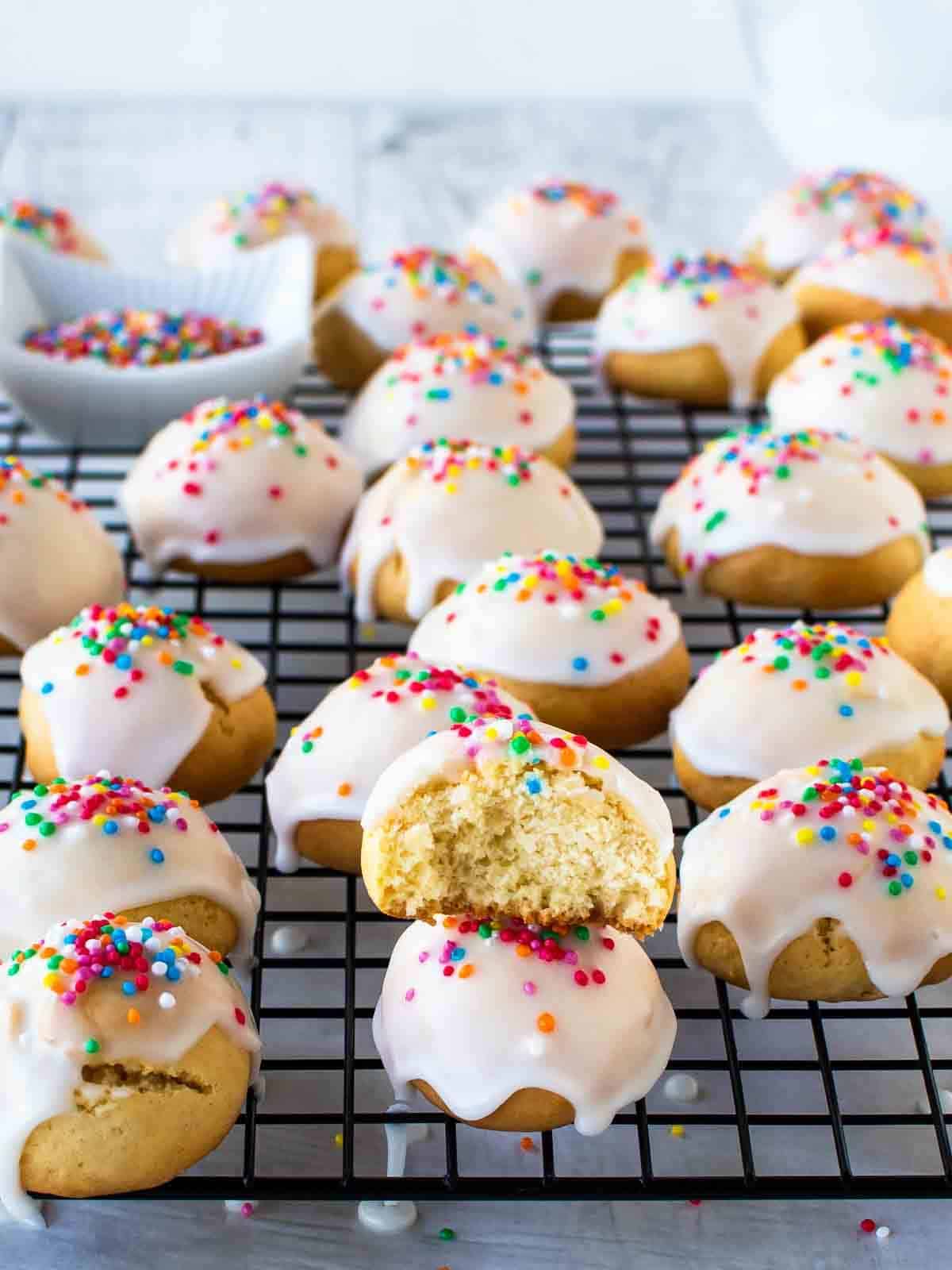 Anise cookies topped with a glaze and sprinkles added on top on a wire cooling rack. 