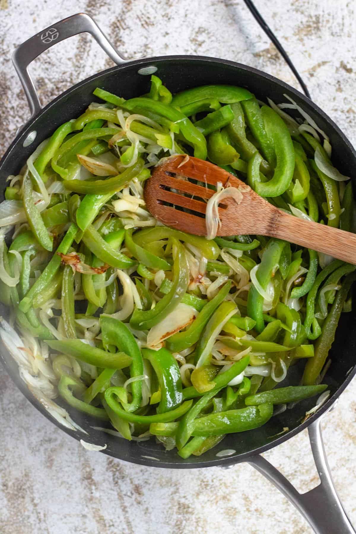 Bell peppers and onions cooking in a skillet. 