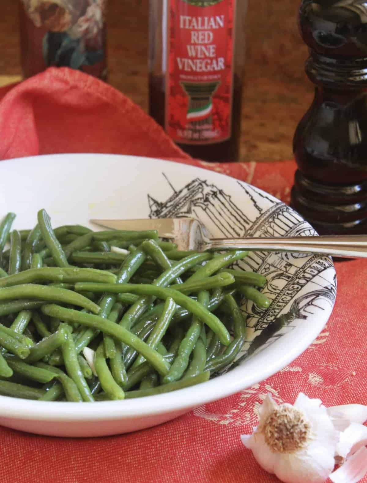 Green bean salad in a bowl with a serving fork in it. 