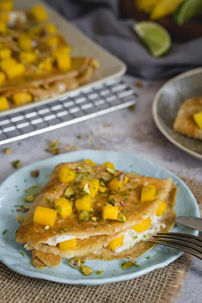 Healthy mango crepes on a plate filled with maple-lime filling. 