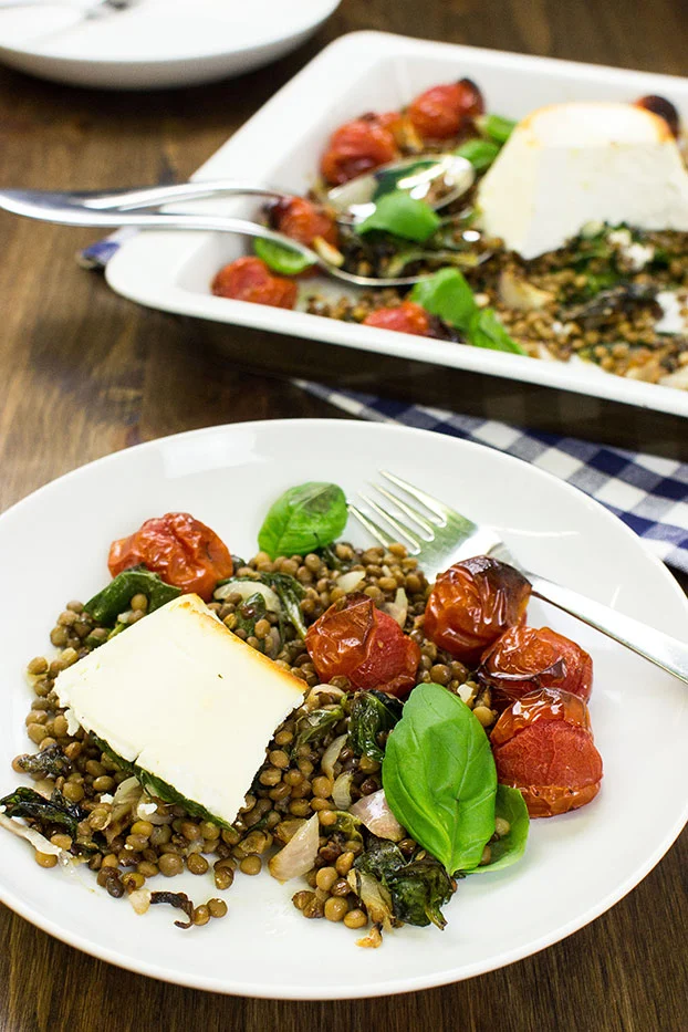 Ricotta bake on a plate with roasted tomatoes and fresh basil. 
