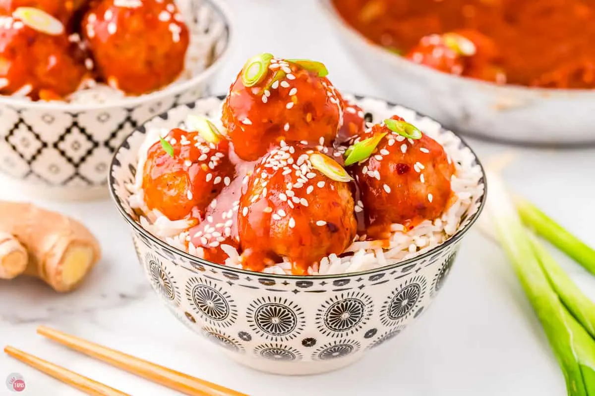 Firecracker meatballs recipe served over rice garnished with green onions. 