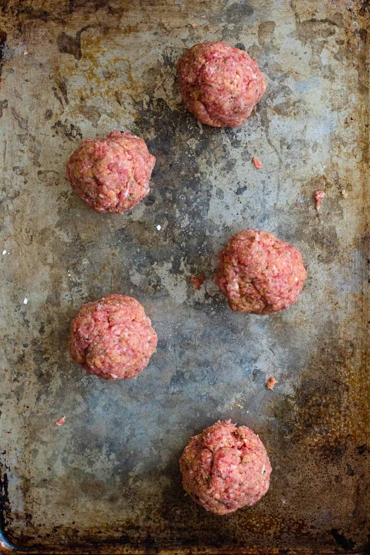 Meatballs formed into balls and placed on a baking sheet. 
