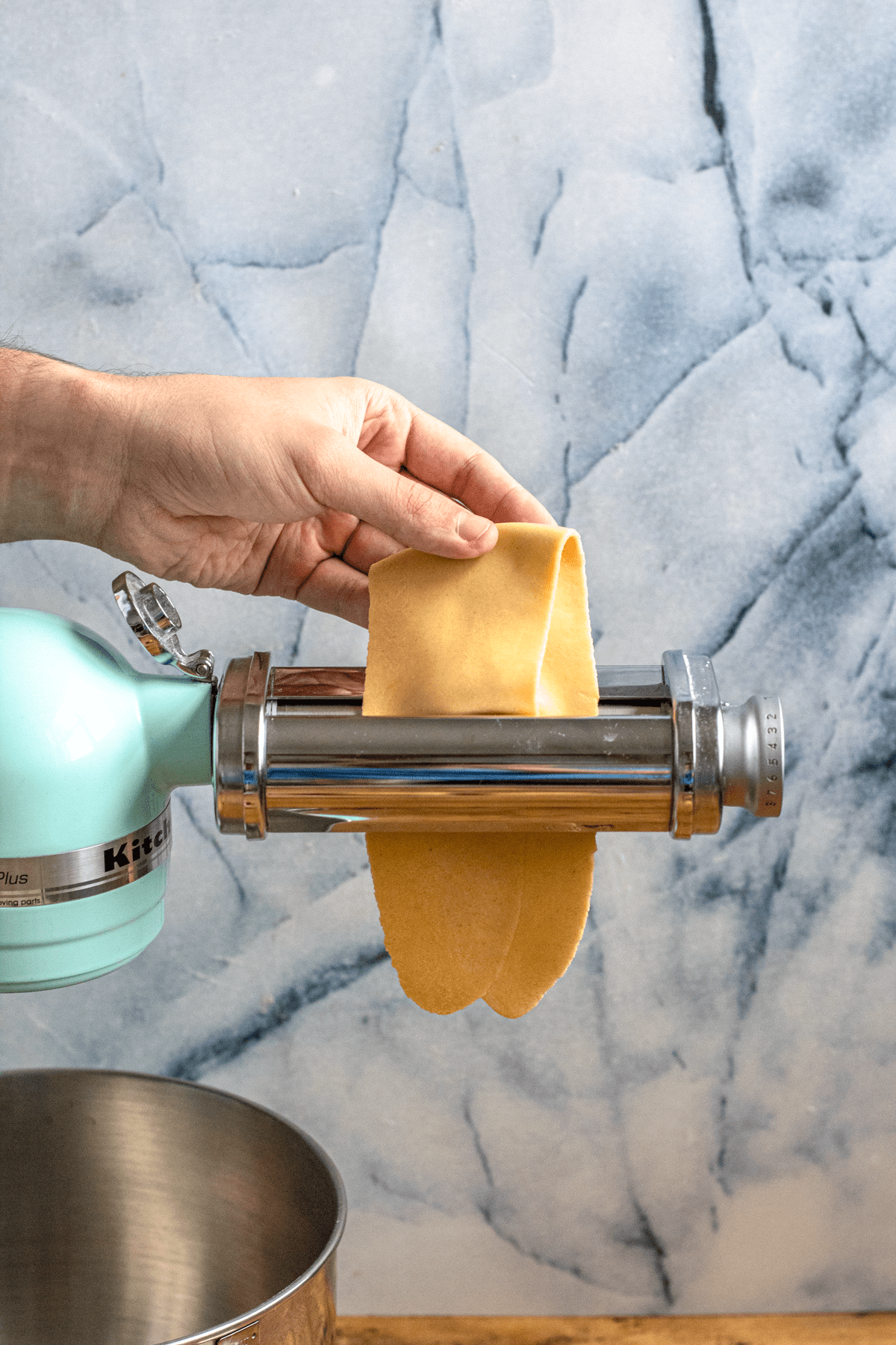 Adding the folded and flattened dough into the pasta maker. 