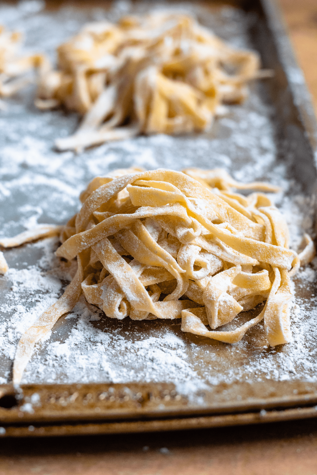 Freshly made pasta dusted with flour on a baking sheet to dry out. 