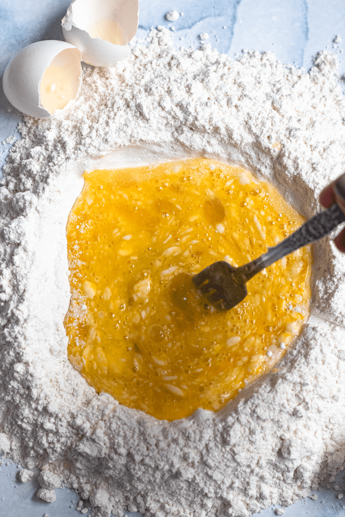 Whisked eggs in the center of a pile of flour. 