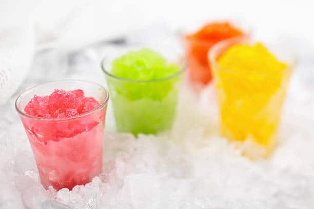 Glass cups of Italian ice sitting on a bed of ice. 