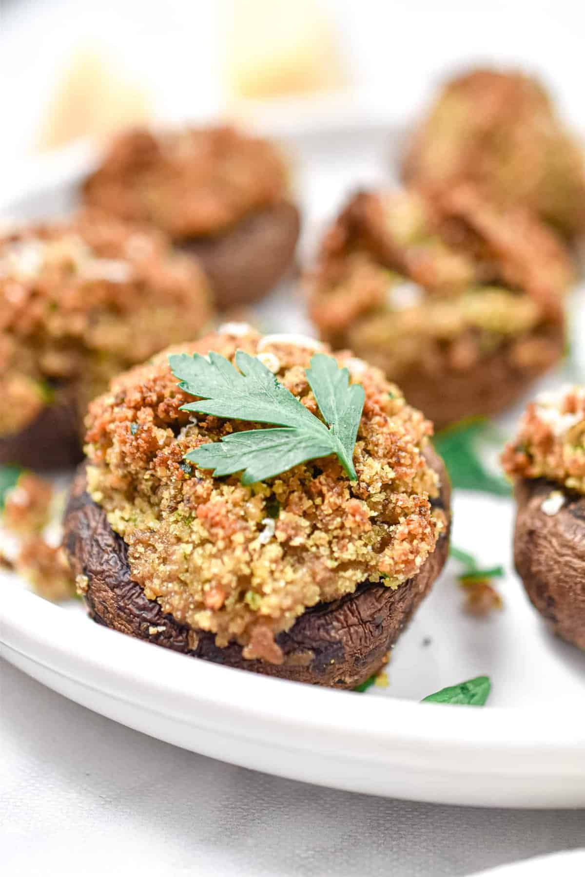 Close up of Italian stuffed mushrooms with a parsley leaf garnished on top of one.