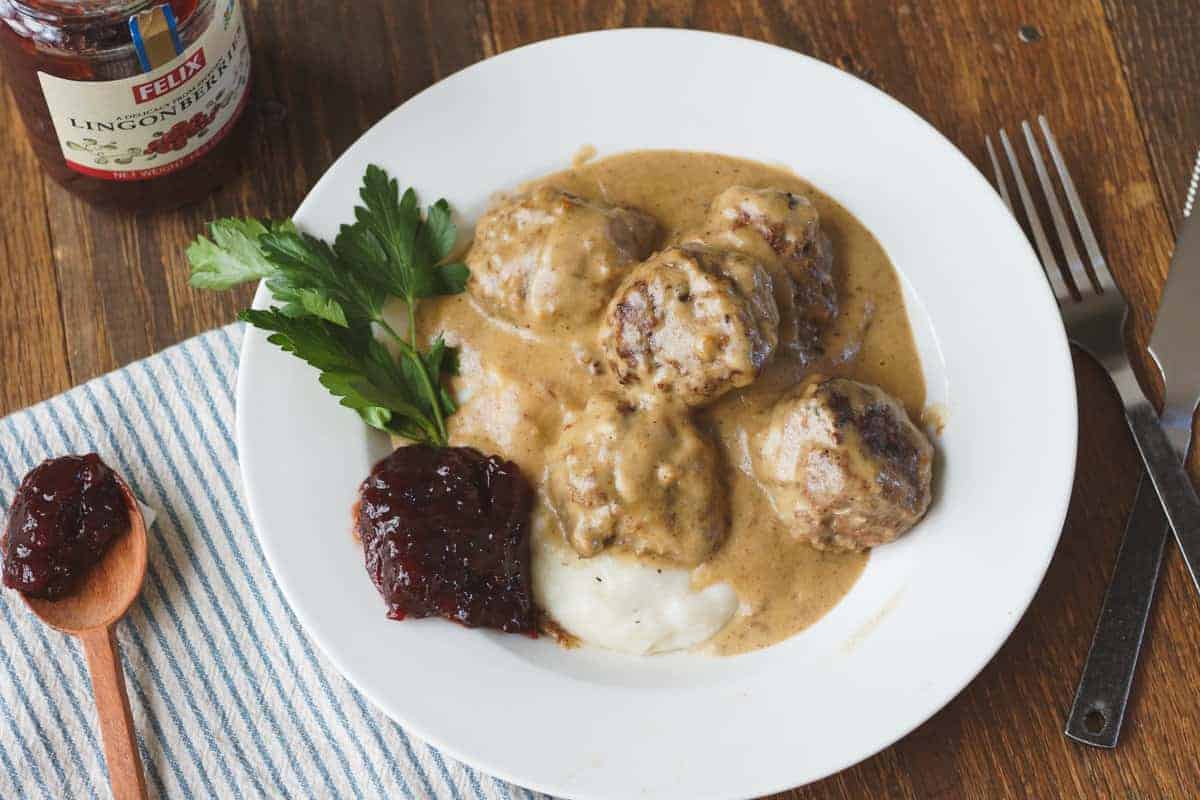 Authentic Swedish meatballs over mashed potatoes and some cranberry sauce on the side. 