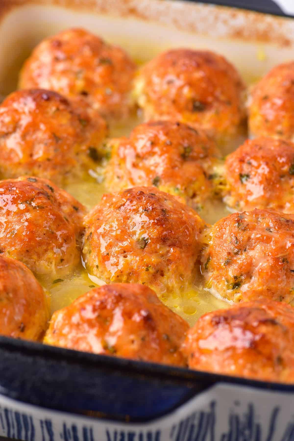Baking dish with baked meatballs in garlic butter. 