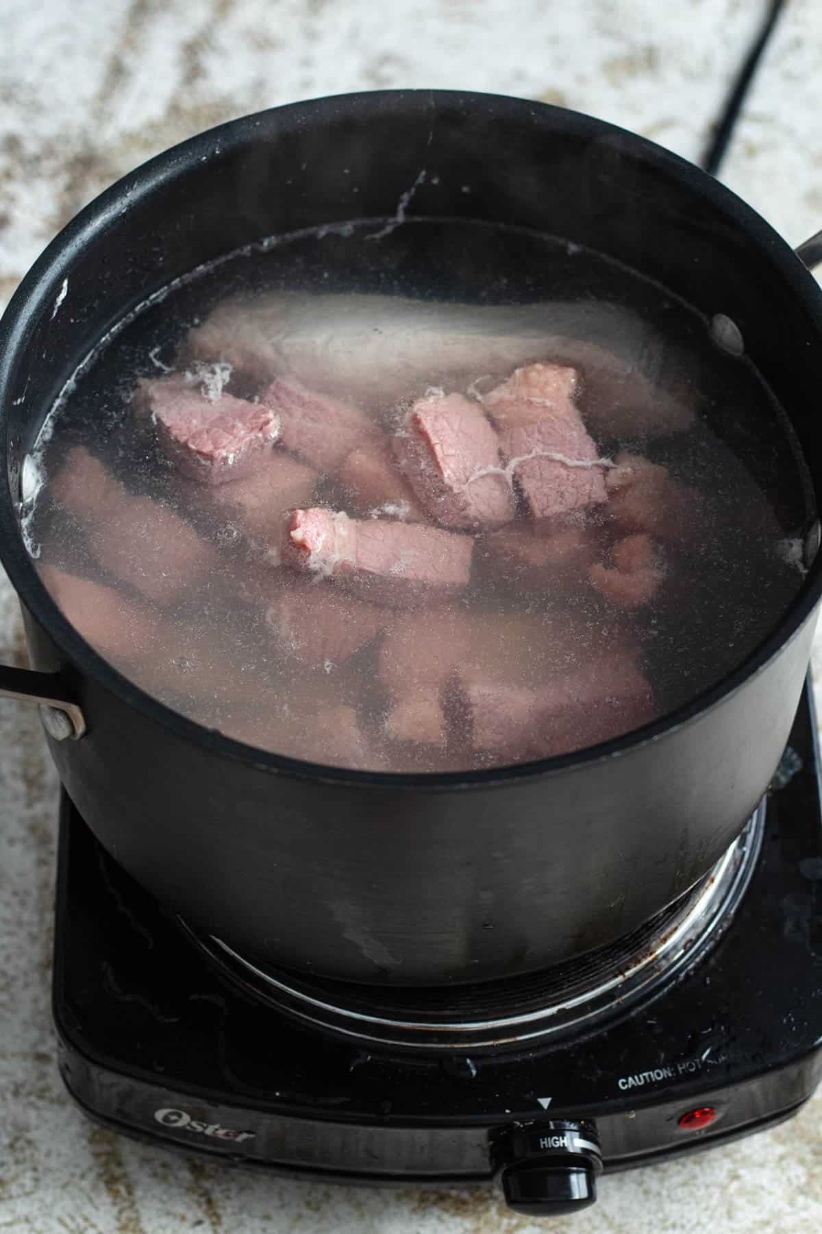 Pot of water with pork ribs and corned beef. 