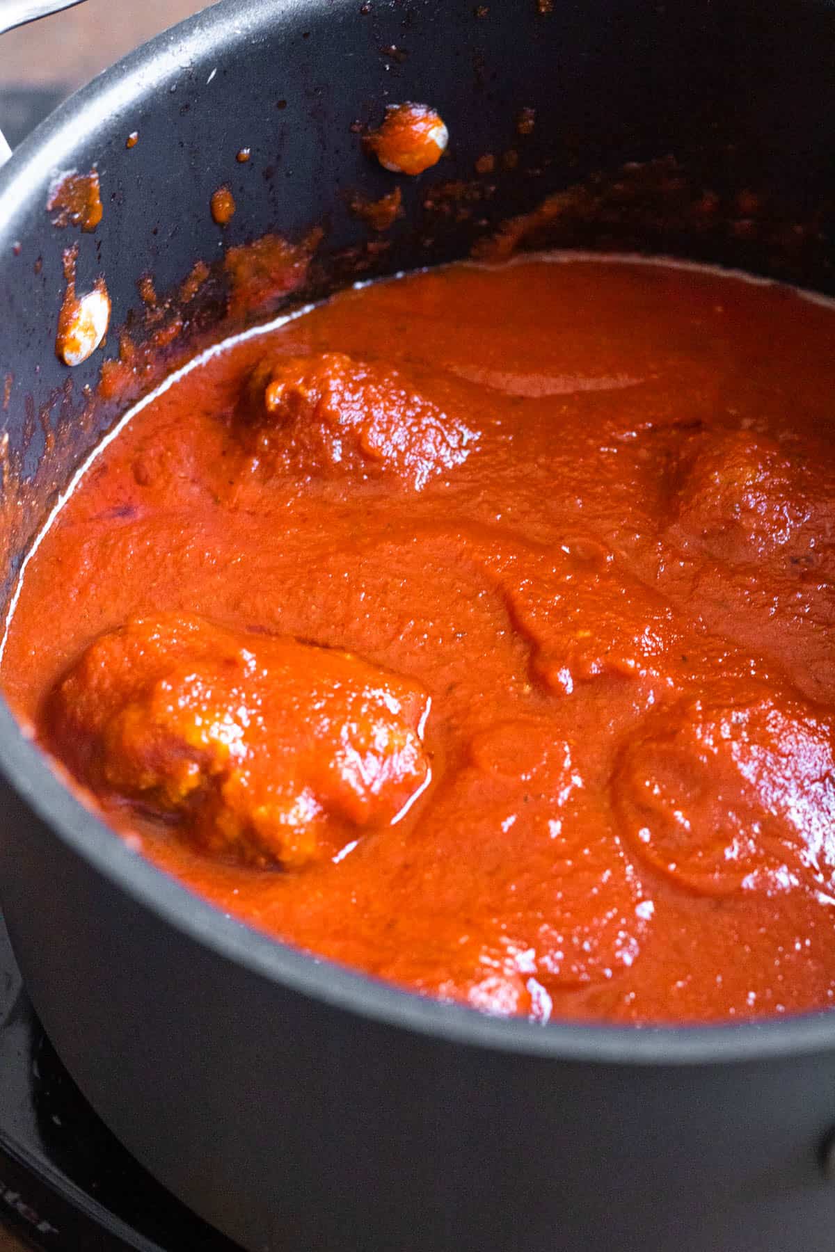 Soft meatballs added to a tomato sauce to cook. 