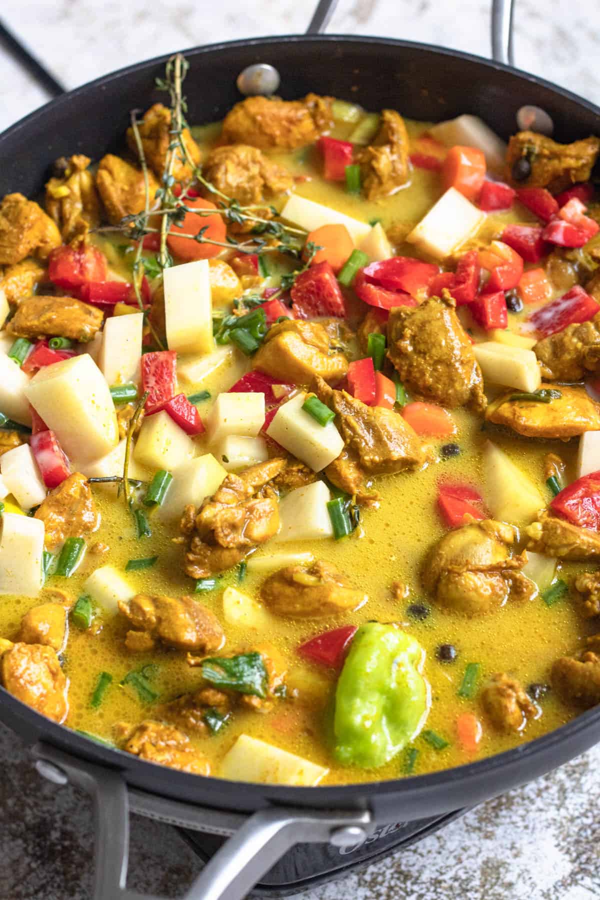 Jamaican chicken curry simmering in a skillet. 